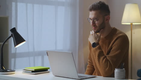 adult-caucasian-man-is-viewing-video-on-display-of-notebook-sitting-in-living-room-using-internet-for-education-and-entertainment-male-portrait-in-home